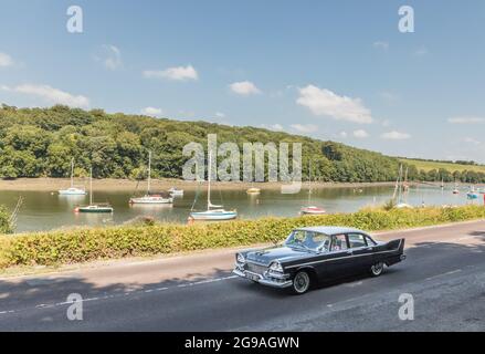 Crosshaven, Cork, Ireland. 25th July, 2021. Bill and Kate Ryan take their 1957 Dodge Kingsway for a sunday drive on a gorgeous summer's day passing moored yachs at Drake's Pool outside Crosshaven, Co. Cork, Ireland.- Credit: David Creedon / Alamy Live News Stock Photo