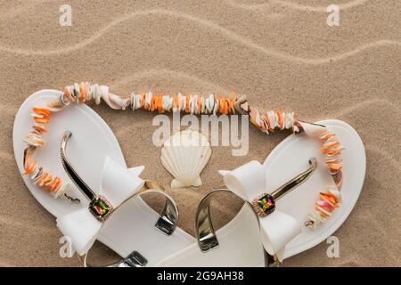 Beach sandals decorated with rhinestones, with beads lying on them made of seashells. With space for design, text place. Top view Stock Photo