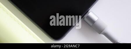 Mobile phone is connected with cable to power bank closeup Stock Photo