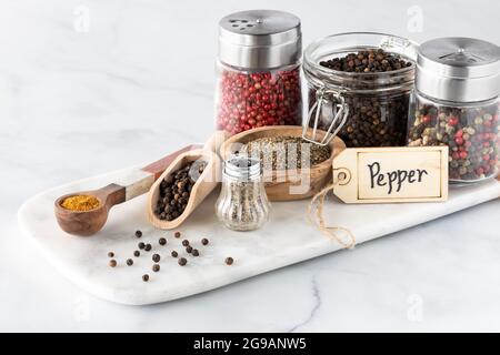 Close up of different types of pepper on a marble slab against a light background. Stock Photo