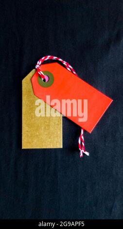 Two colored tags on a white rope, black background. Vertical photography. Copy space, place for text, flat lay. vertical position of the photo. Stock Photo