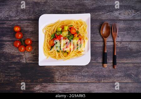 Home-cooked linguine pasta with vegetables on a rustic wooden table. Stock Photo