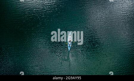 Aerial bird eye shot of a canoe with two person paddling, on beautiful turquoise lake wate
