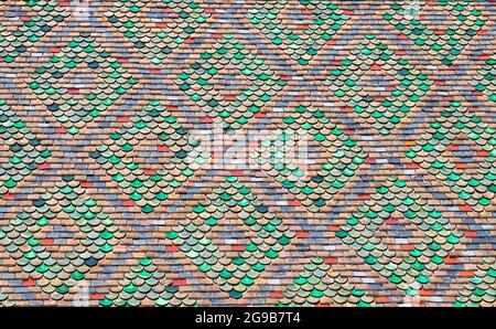 The roof is made of colored tiles. Old roof made of colored tiles. Background. The roof is in a pattern. Texture, pattern, ornament from old colorful Stock Photo