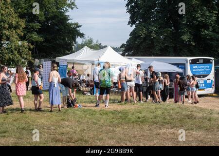 Southwold, UK. 25 July 2021. Festival goers queue for Coronavirus Vaccines, at an NHS community vaccination team bus, on the third day of the Latitude festival in Henham Park, Southwold, Suffolk. The walk-in service is a joint venture between Norfolk and Waverley CCG and GM graham pharmacies. Picture date: Sunday July 25, 2021. Photo credit should read: Matt Crossick/Empics/Alamy Live News Stock Photo