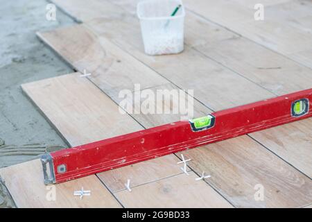 The hands of the professional tiler lying or installing modern, ceramic tile above cement on the garden terrace , tiling floor, building and pavement Stock Photo