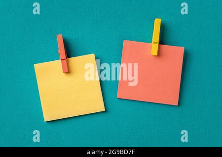 Yellow and orange adhesive stickers with wooden clothespins over textured teal turquoise background. Plan tasks, share ideas, creativity concepts. Stock Photo