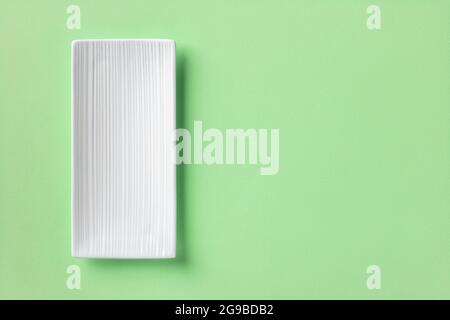 White rectangular ceramic plate over mint green textured background. Empty flat plate with grooved corrugated surface for stylish food design mockup. Stock Photo