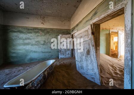 Abandoned building being taken over by encroaching sand in the Kolmanskop ghost town near Luderitz, Namib Desert, Namibia. Stock Photo