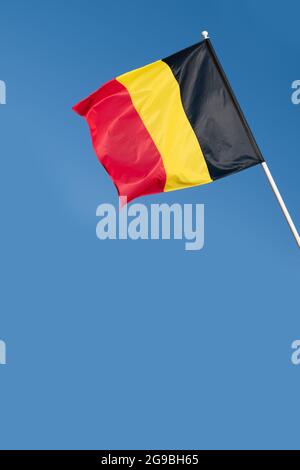 Flag of Belgium on blue sky background. Belgian flag waving in wind Stock Photo