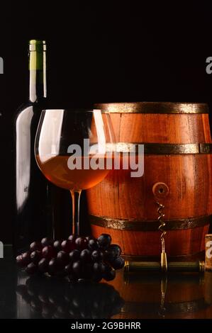 Glass and bottle of wine and a wooden barrel on the table Stock Photo