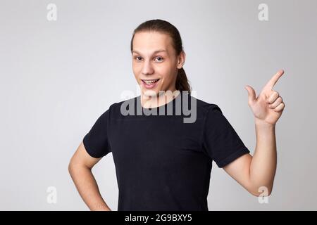 Positive young man pointing up at empty space Stock Photo