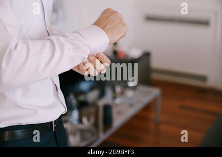 Groom buttons up the buttons on the cuff of a white shirt Stock Photo