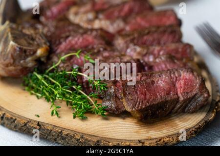 Sliced medium rare grilled beef steak on wooden cutting board with spices Stock Photo