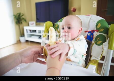 woman giving banana to her baby Stock Photo