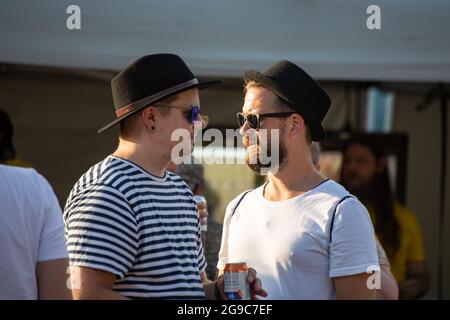 Two men facing each other wearing hats and sunglasses at open-air concert in Helsinki, Finland Stock Photo