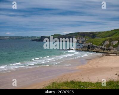 The pristine sand of Whiterocks Beach and coastal cliffs on the Antrim Causeway Coast in Northern Ireland, UK. Taken on a sunny day in summer with lig Stock Photo
