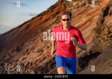 Fit runner man sport athlete trail, running outside on volcano mountain in desert. Motivation and focus during exercise. Fitness and health. Stock Photo
