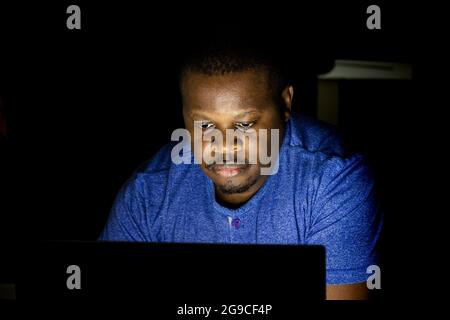 African male looking at laptop screen in the dark Stock Photo