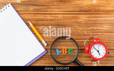 Notepad with school supplies on a wooden desk. Stock Photo