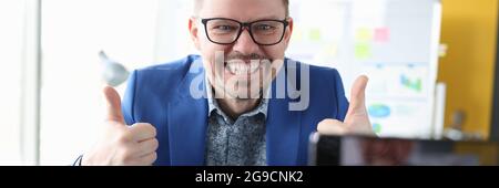 Man looking into camera of mobile phone and showing thumb up Stock Photo