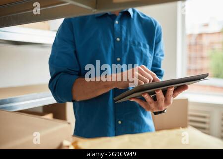 Cropped shot of young man using digital tablet in warehouse while doing inventory and managing small business, copy space Stock Photo