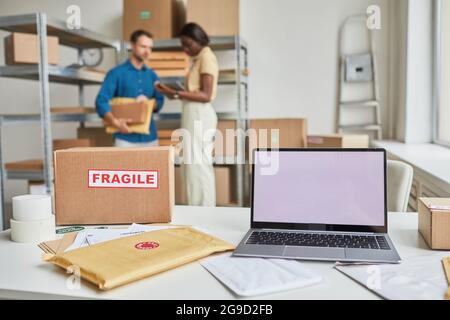 Background image of opened laptop with blank screen in warehouse, small business and shipping service concept, copy space Stock Photo
