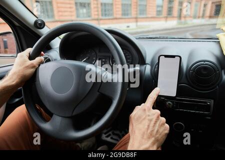 Close up of unrecognizable man driving car focus on hand tapping at smartphone with blank screen, copy space Stock Photo