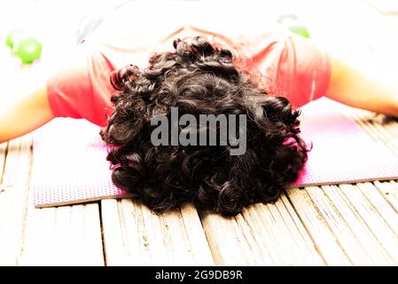 brown-haired girl in a red sports T-shirt on a pink mat practice yoga Stock Photo