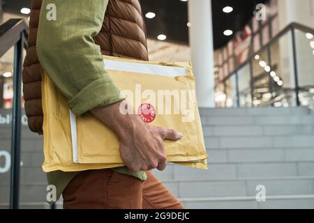 Close up of unrecognizable delivery man holding parcels while entering office building, copy space Stock Photo