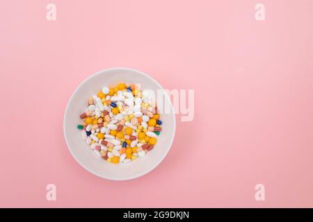 Global Pharmaceutical Industry and Medicinal Products - Colored Pills and Capsules in White Dish on Pink Background Stock Photo