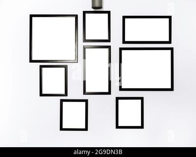 Group of mockup photo frames. White square picture with black frame mockup hanging on the white wall background. Stock Photo