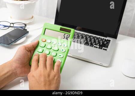 Accountant working and analyzing financial calculating with calculator and laptop computer income-expenditure at office desktop, Business financial an Stock Photo