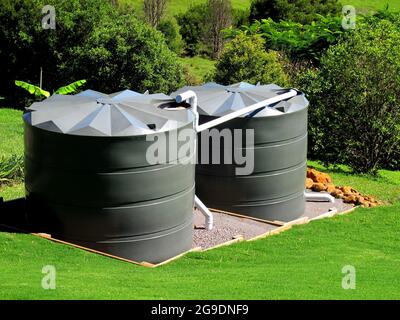 Two large green water tanks on hillside Stock Photo