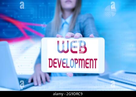 Writing displaying text Web Development. Word for work involved in developing a website for the Internet Business Woman Sitting In Office Holding Stock Photo