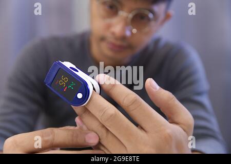 Man measuring his own oxygen   Using a Fingertip Pulse Oximeter. Put the probe on the middle finger that gives the most accurate measurement.Select a Stock Photo