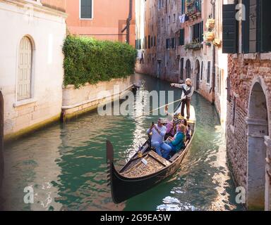 VENICE, ITALY - OCTOBER, 07 2017 Tourists travel on gondola on small canal. Gondola trip is the most popular touristic activity in Venice Stock Photo