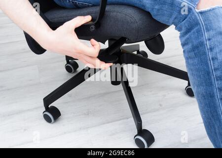 Man checks lifting mechanism of chair. Assembling office chair indoors Stock Photo