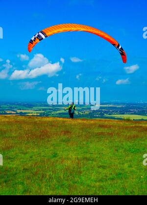 A man with an orange parasail attempting to take off in too little wind on the yorkshire moors Stock Photo
