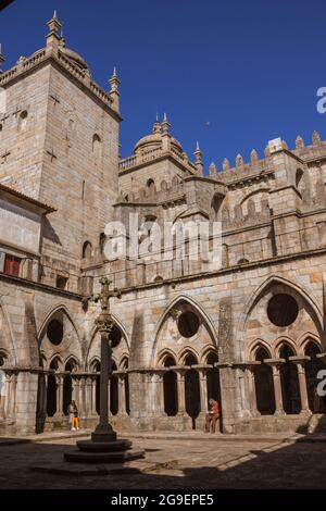Gothic cloisters in the Roman Catholic Cathedral So de Porto, built in the 17th century.  Two people sitting on the ledges reading a book. Stock Photo
