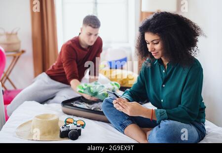 Happy young couple preparing and packing for summer holiday at home. Stock Photo