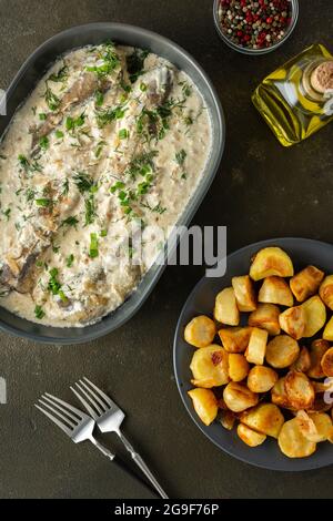 Stewed hake in a creamy sauce with baked potatoes, delicious hearty lunch, top view Stock Photo