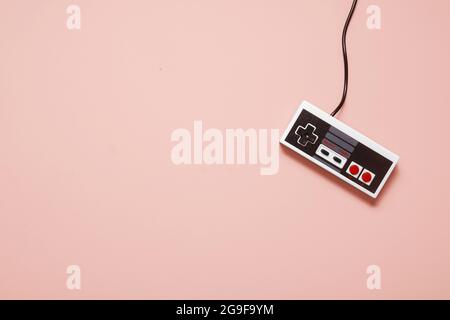 Retro vintage white game console controller on a pastel pink background with copy space and room for text Stock Photo