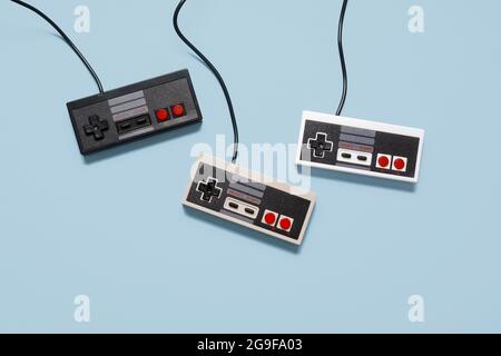 Three retro vintage game console controllers on a pastel blue background with copy space and room for text Stock Photo