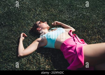 Woman lying down in grass day dreaming in summer. Feeling good optimism. Healthy gorgeous pretty model relaxing in carefree mood. Peaceful rest. Stock Photo