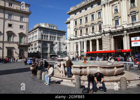 ROME, ITALY - APRIL 10, 2012: People sit by the fountain at Piazza Colonna square in Rome. According to official data Rome was visited by 12.6 million Stock Photo