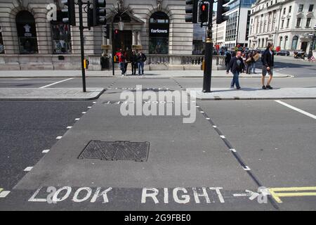 LONDON, UK - MAY 13, 2012: People cross the street in London. Look Right and Look Left warning signs are typical for crosswalks in the UK. Stock Photo