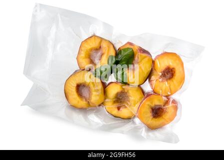 Peaches cut in half with mint leaves in vacuum packed sealed for sous vide cooking isolated on white Stock Photo