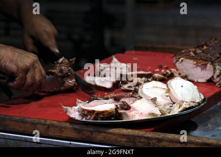 Close up of the hands of a cook cutting roast meat Stock Photo