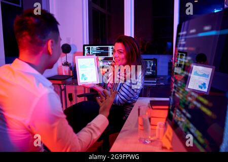Team of coders discussing reports and statistics when working in office late at night Stock Photo